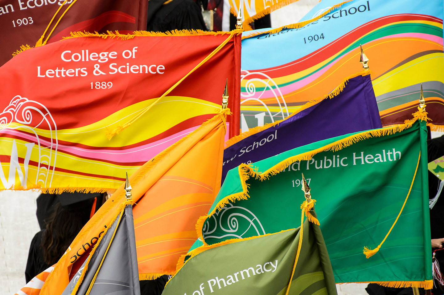 Colorful UW flags blow in breeze at graduation ceremony at Camp Randall Stadium at the University of Wisconsin-Madison.