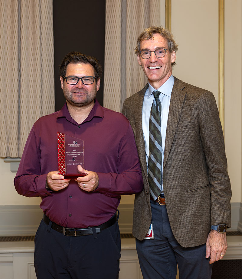 Andrew Quanbeck, PhD, holds award, standing next to David Rakel, MD.