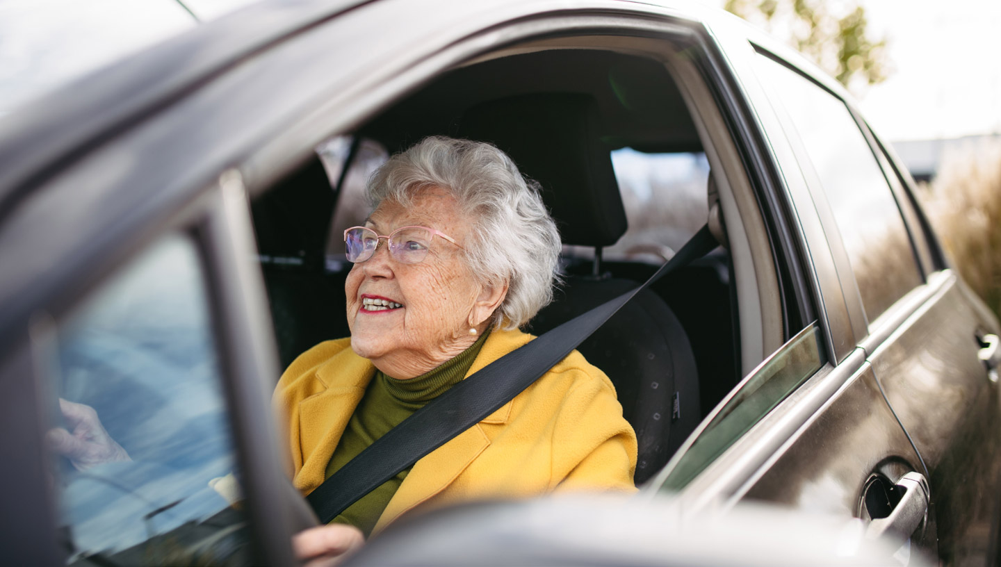 Smiling senior woman driving car.