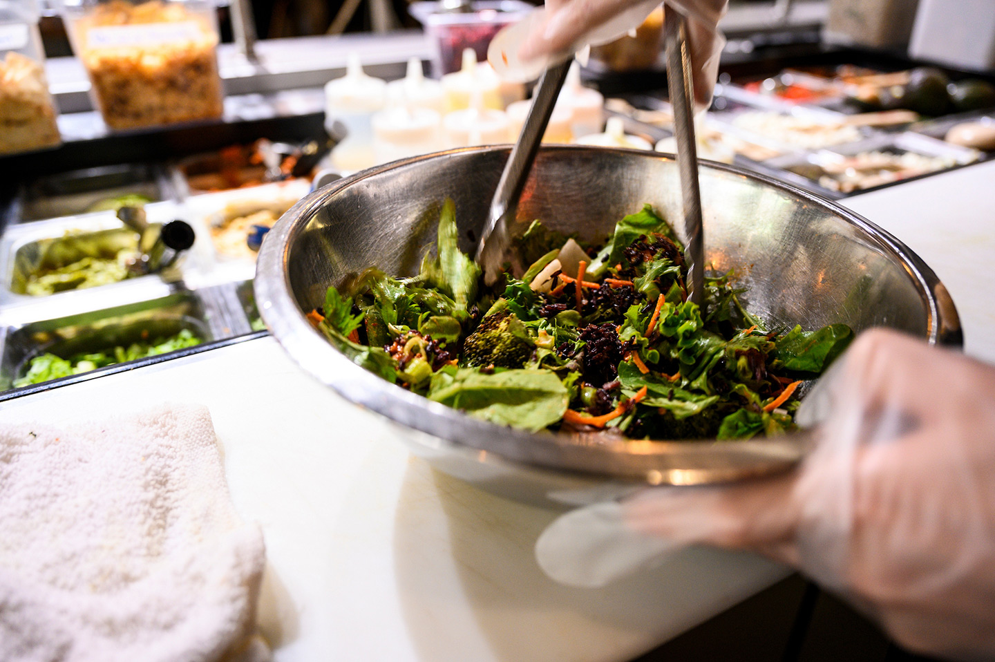 Kitchen staff prepare a freshly-made and healthy salad fast food for patrons.