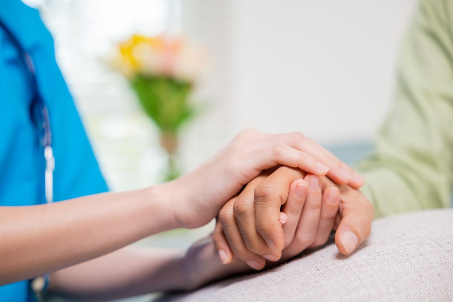 Close up of hands showing a caring nurse cupping a patient's hand in both of hers.
