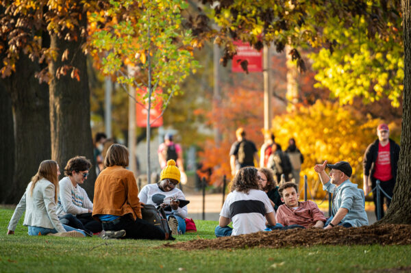 Group gathers outdoors in fall setting for class discussion.