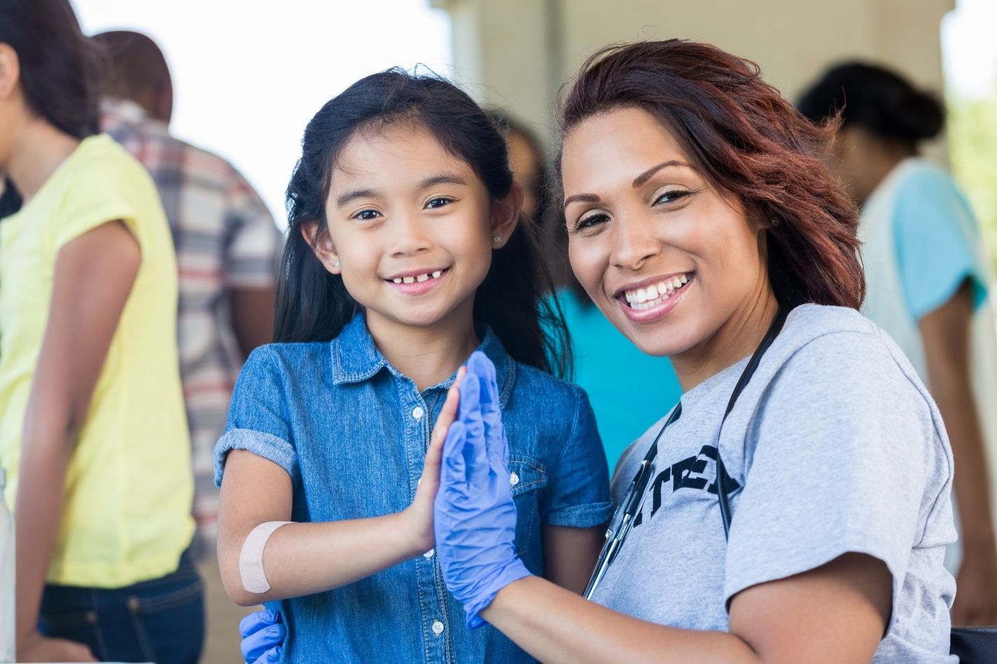 Young patient and female doctor high five during a community health fair.