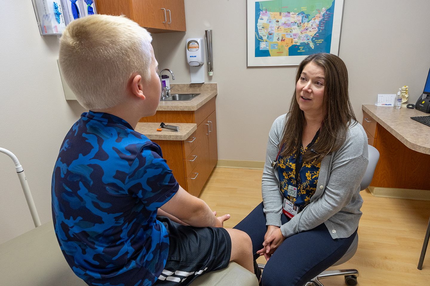 A female doctor examines a boy in a clinical exam room.