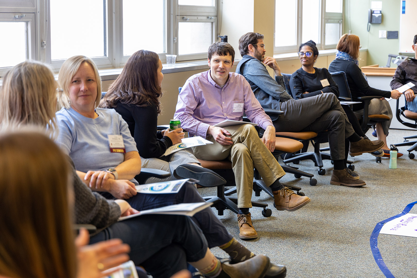 Faculty and staff sit in a circle pairing up with a partner for a discussion about whole health.