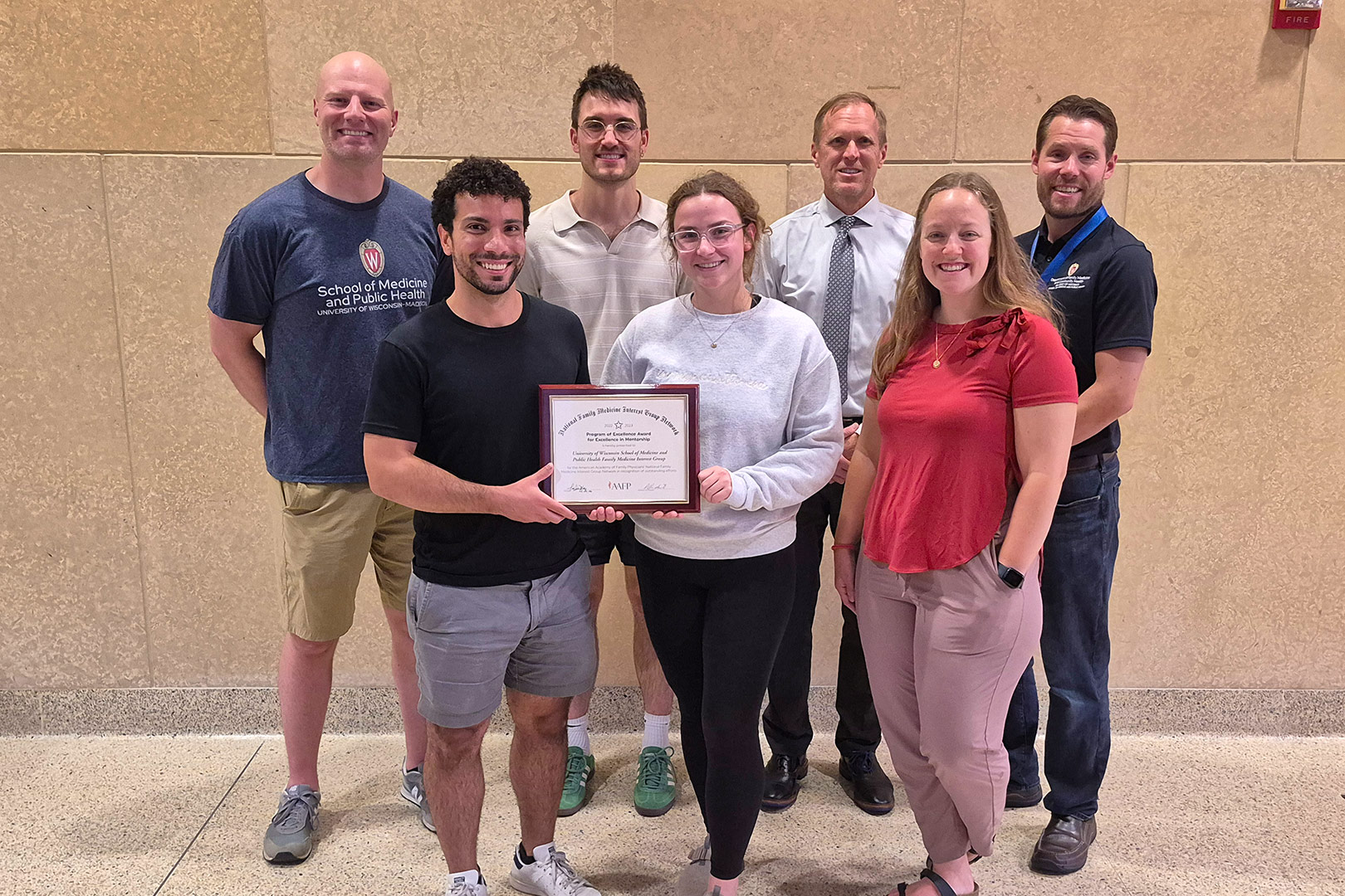 FMIG students, faculty, and staff pose with Program of Excellence Award plaque.