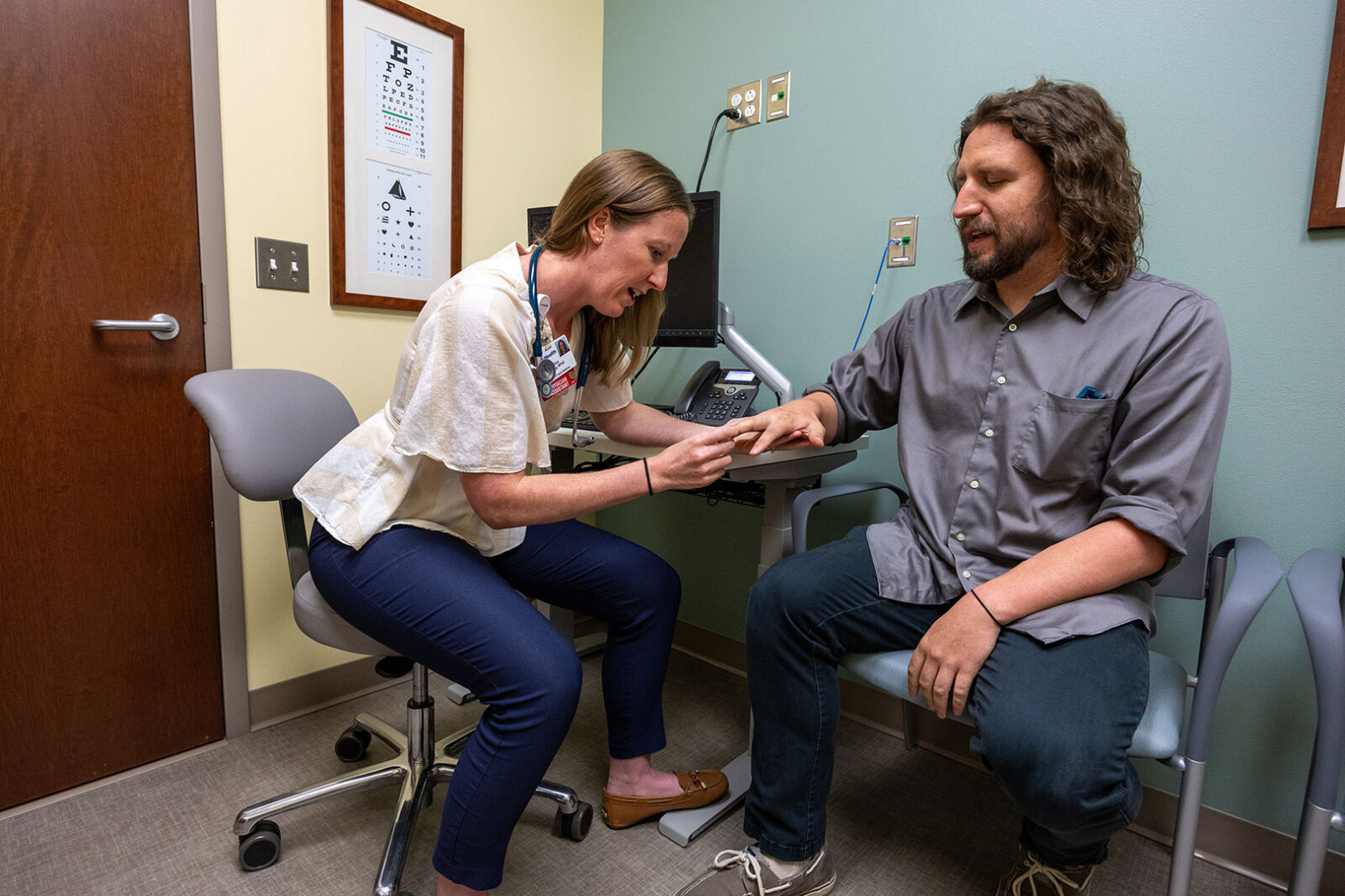 Doctor examining a patient's hand in a clinic room.
