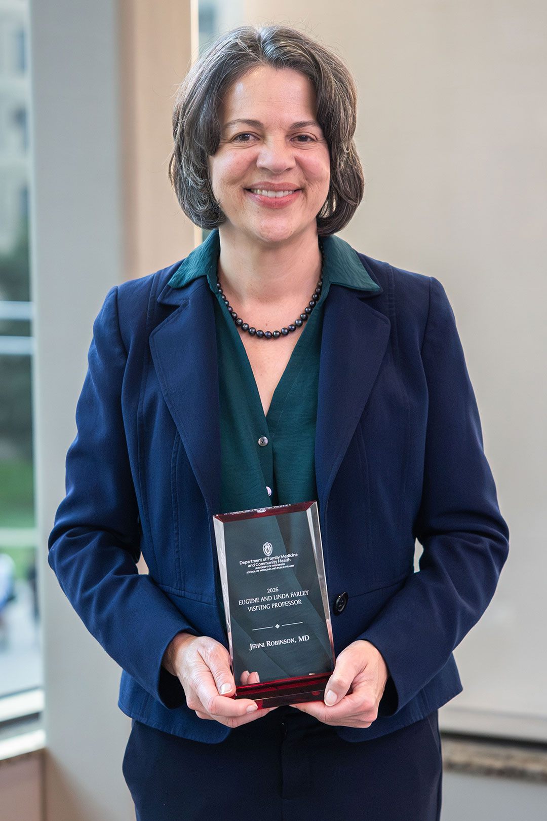 Dr. Jehni Robinson holds a Eugene and Linda Farley Visiting Professorship plaque.