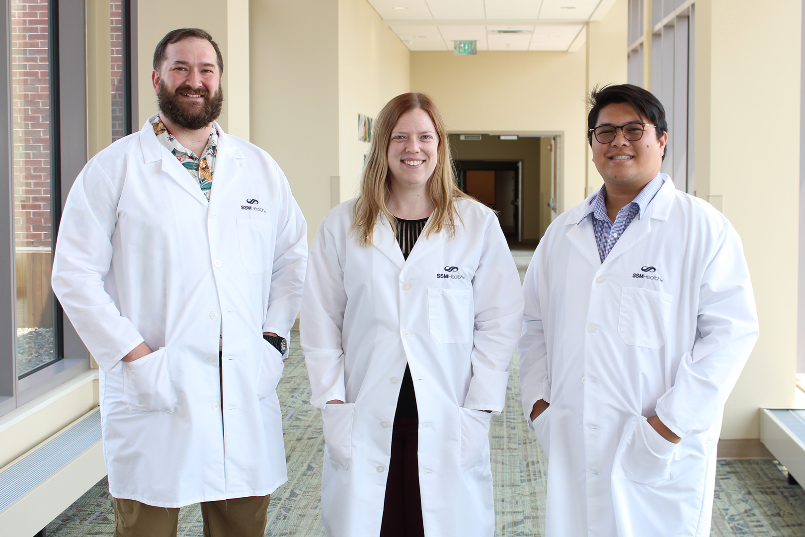 Monroe Residents wearing white coats stand in a brightly lit hospital hallway.