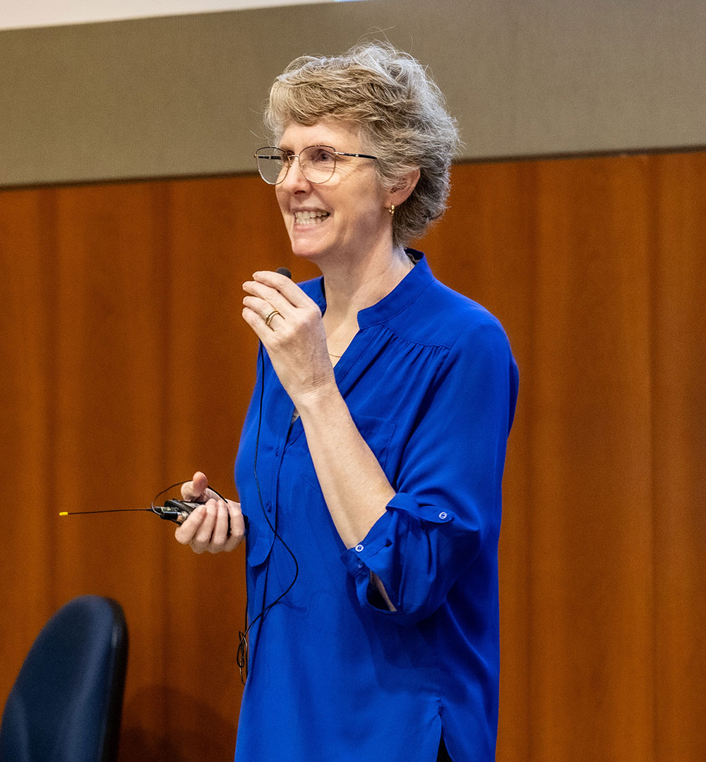 Dr. Ann Evensen speaking into a small handheld microphone.
