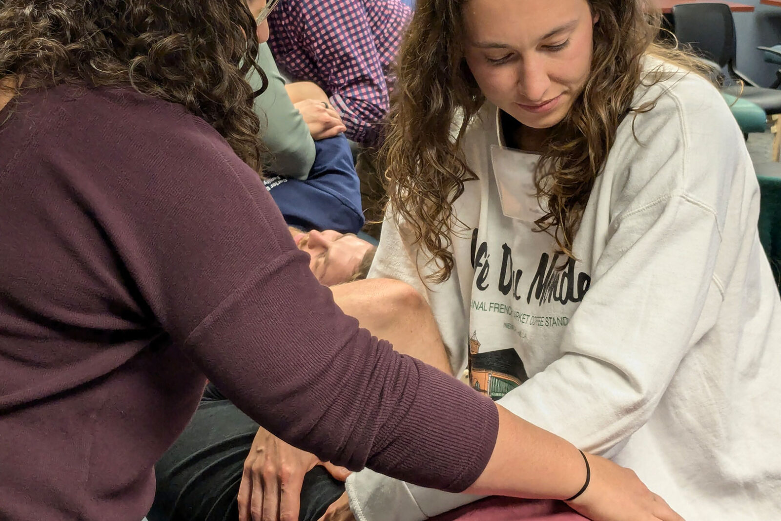 An osteopathic faculty member is teaching a resident, demonstrating a technique on a patient.
