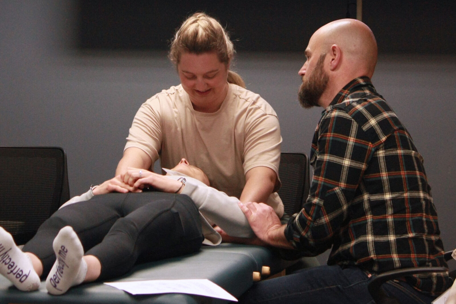 An osteopathic faculty member is teaching a resident who is demonstrating a technique on a patient.