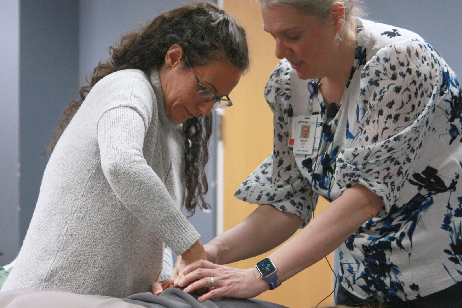 An osteopathic faculty member assists a resident in learning correct hand placement.